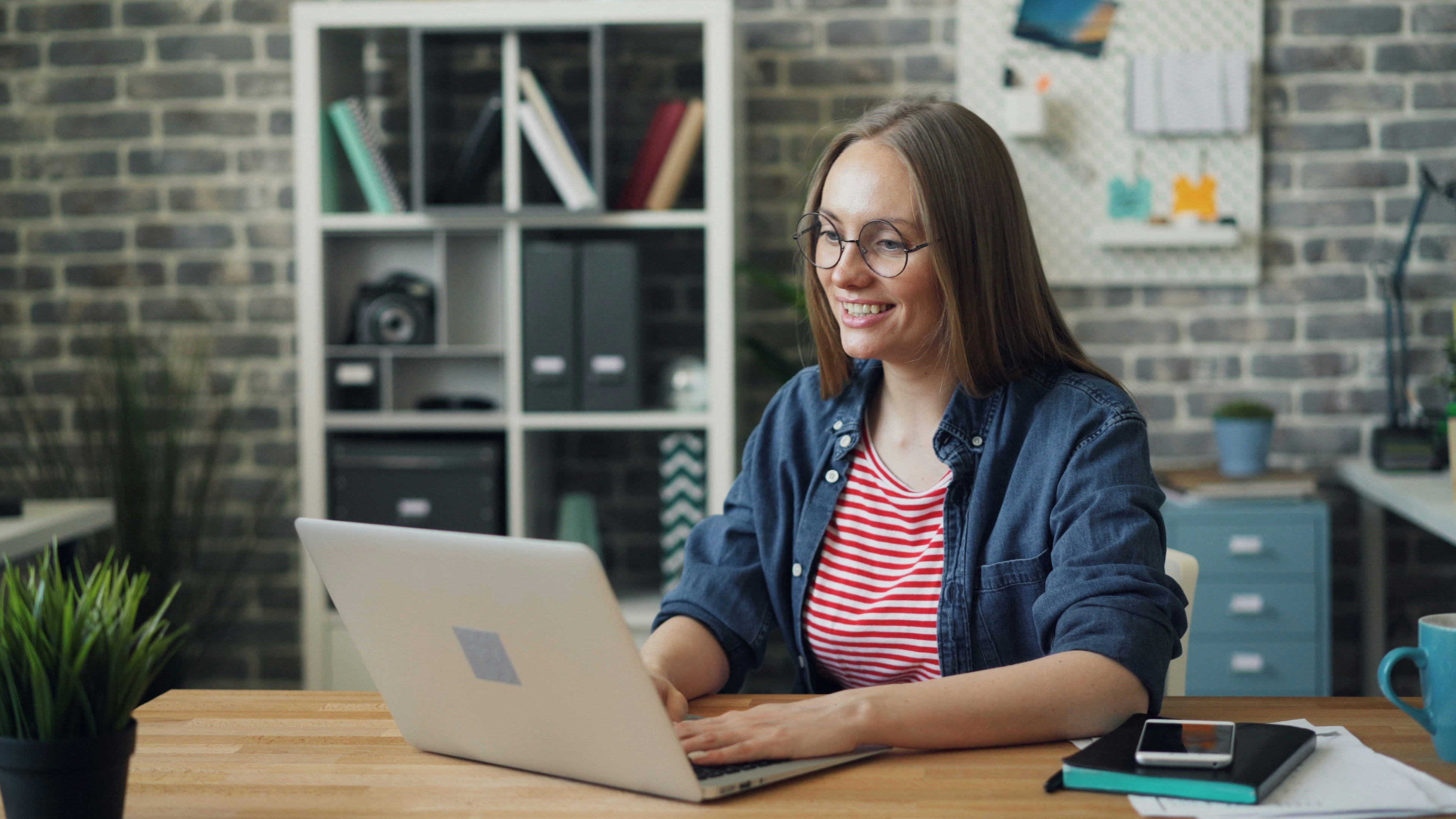 Donna sorridente usa laptop per psicoterapia online in un ambiente domestico.